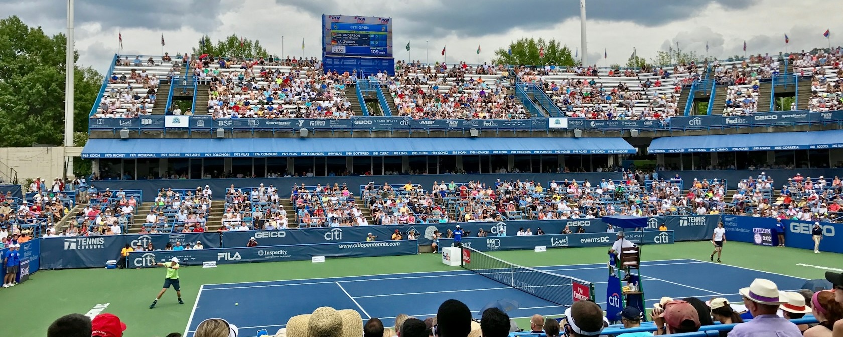 Tennis match in progress at the Citi Open with a crowd of spectators in the stands at the venue in Washington, DC.