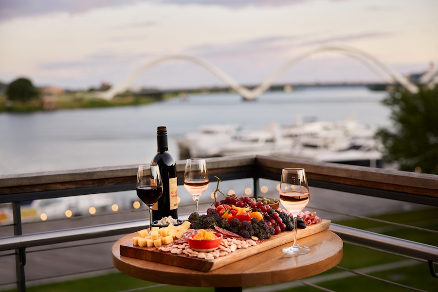 A spread of wine and charcuterie on the patio of District Winery with a view of the river in the background. 