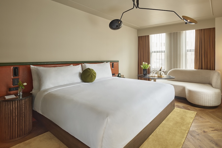 Stylish king room at Sixty DC featuring a minimalist bed, modern lighting and mid-century inspired furniture.