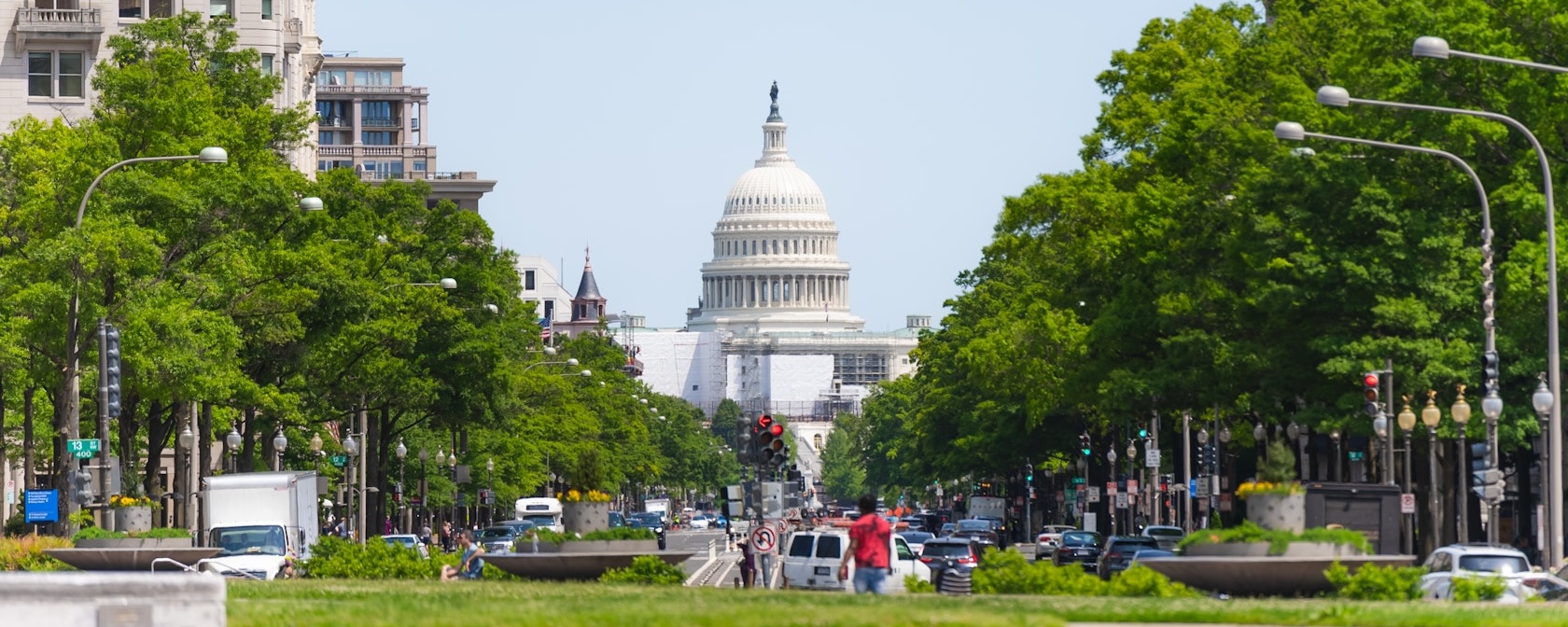 A wide view of Pennsylvania Avenue, lined by trees and leading toward the U.S. Capitol Building.