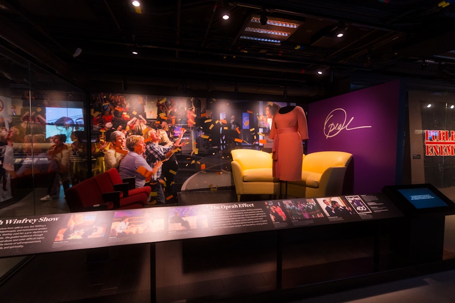 Exhibit featuring Oprah Winfrey’s stage set with yellow chairs and a dress at the National Museum of African American History and Culture.