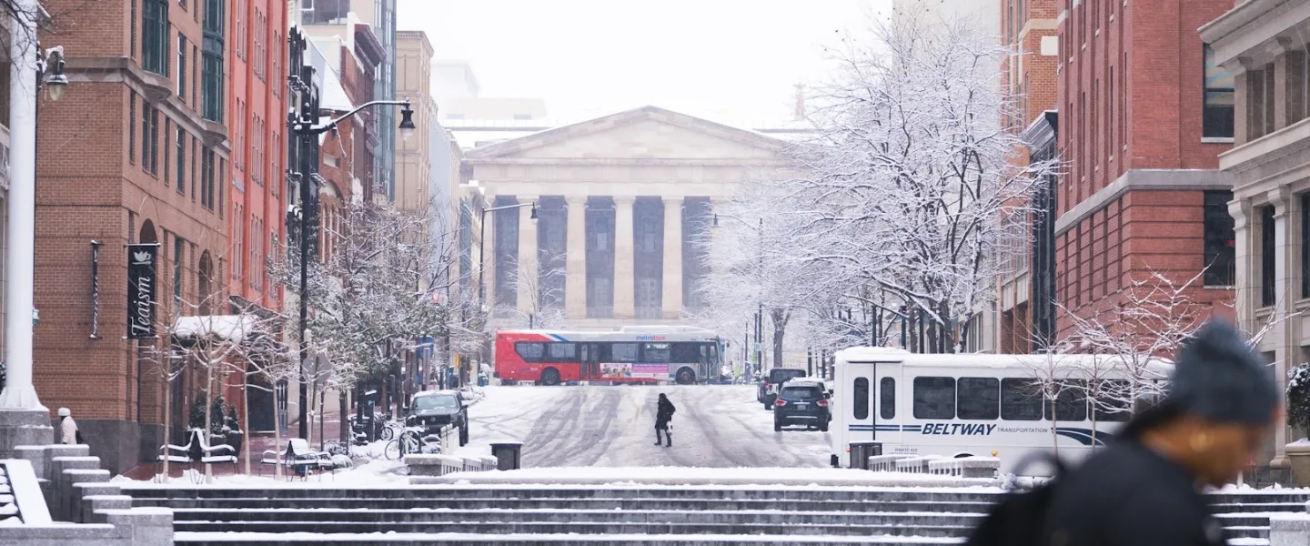 A snowy scene of a downtown street leading up to the National Archives in Washington, DC. 