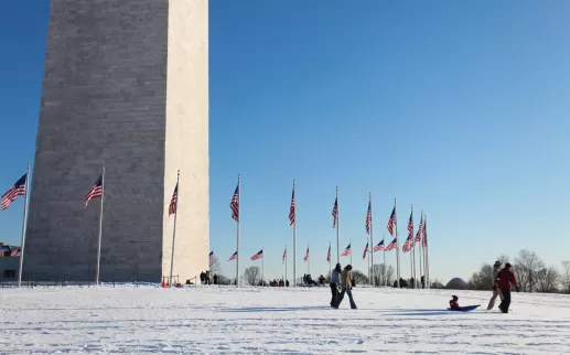 Family on snowy Washington Monument grounds on the National Mall - The best snow day activities in Washington, DC
