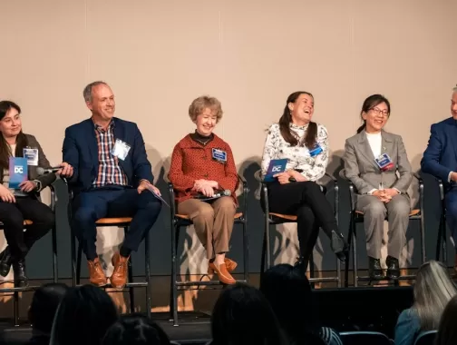 A stage of professional panelists smiling and laughing. 