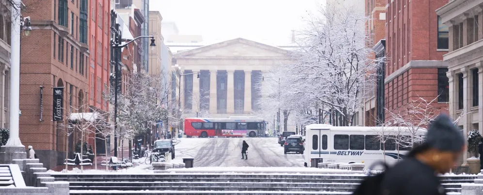 A snowy scene of a downtown street leading up to the National Archives in Washington, DC. 